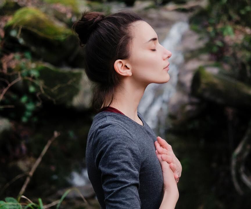 Frau meditierend vor Wasserfall